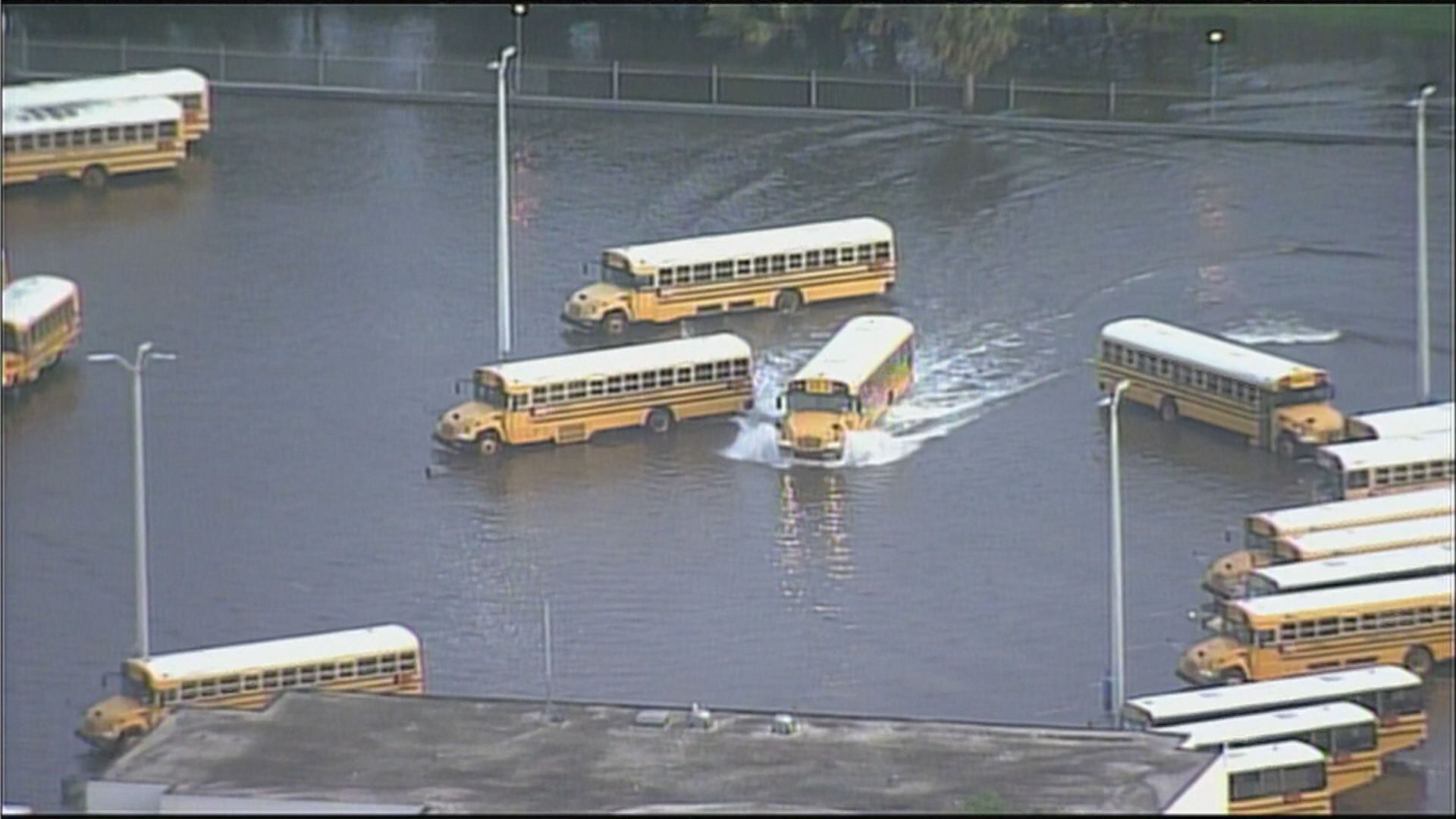 School buses make their way through a flooded parking lot Tuesday morning in Fort Lauderdale.