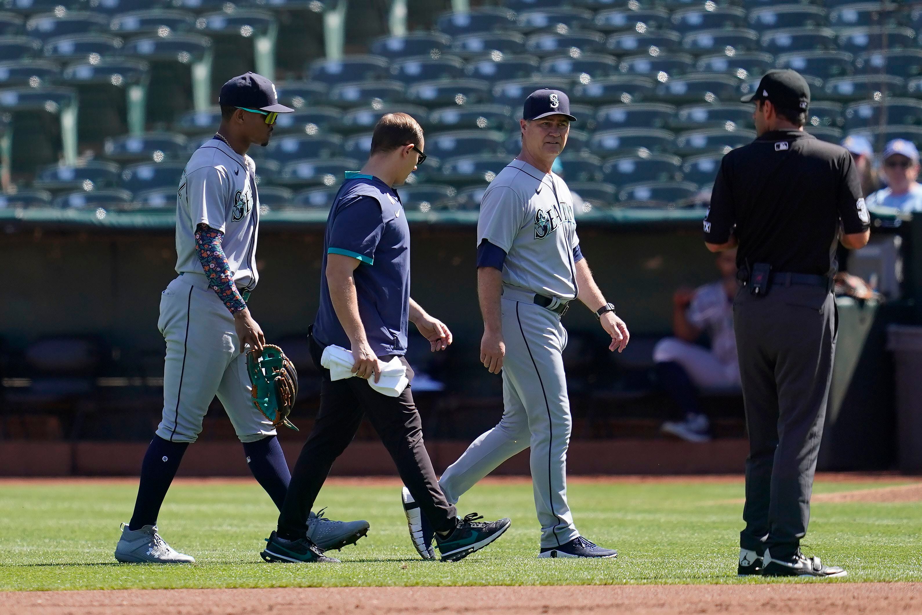 Seattle Mariners' Jarred Kelenic holds his head after a collision